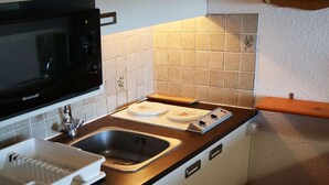A compact kitchen with a black microwave, a sink, and a wooden countertop. - STUDIO N° 0309 LE CAIRN (LES ORRES)