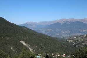 A mountainous landscape with a valley, a small settlement, and a clear sky.