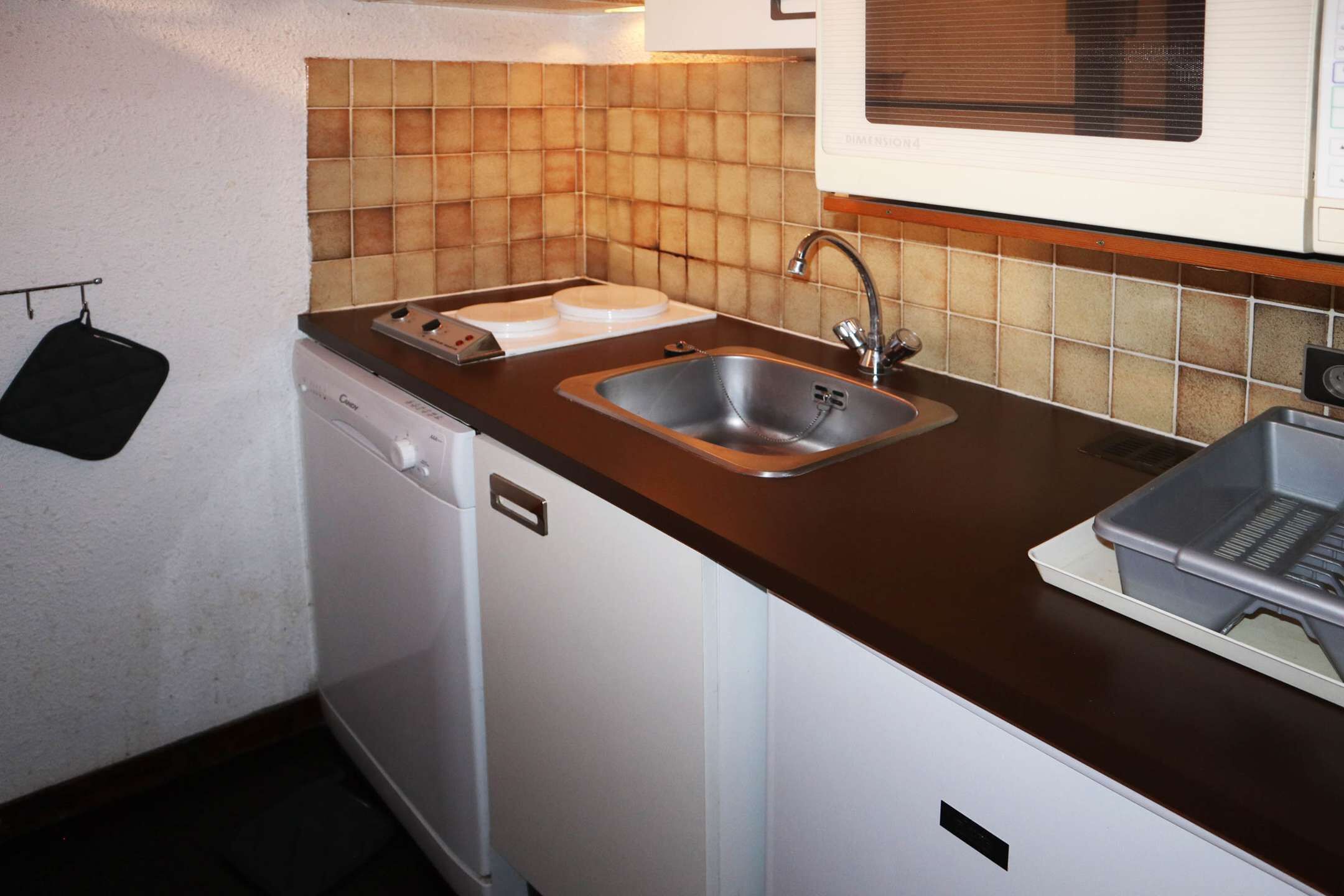 A compact kitchen with a dishwasher, a sink, and a microwave.