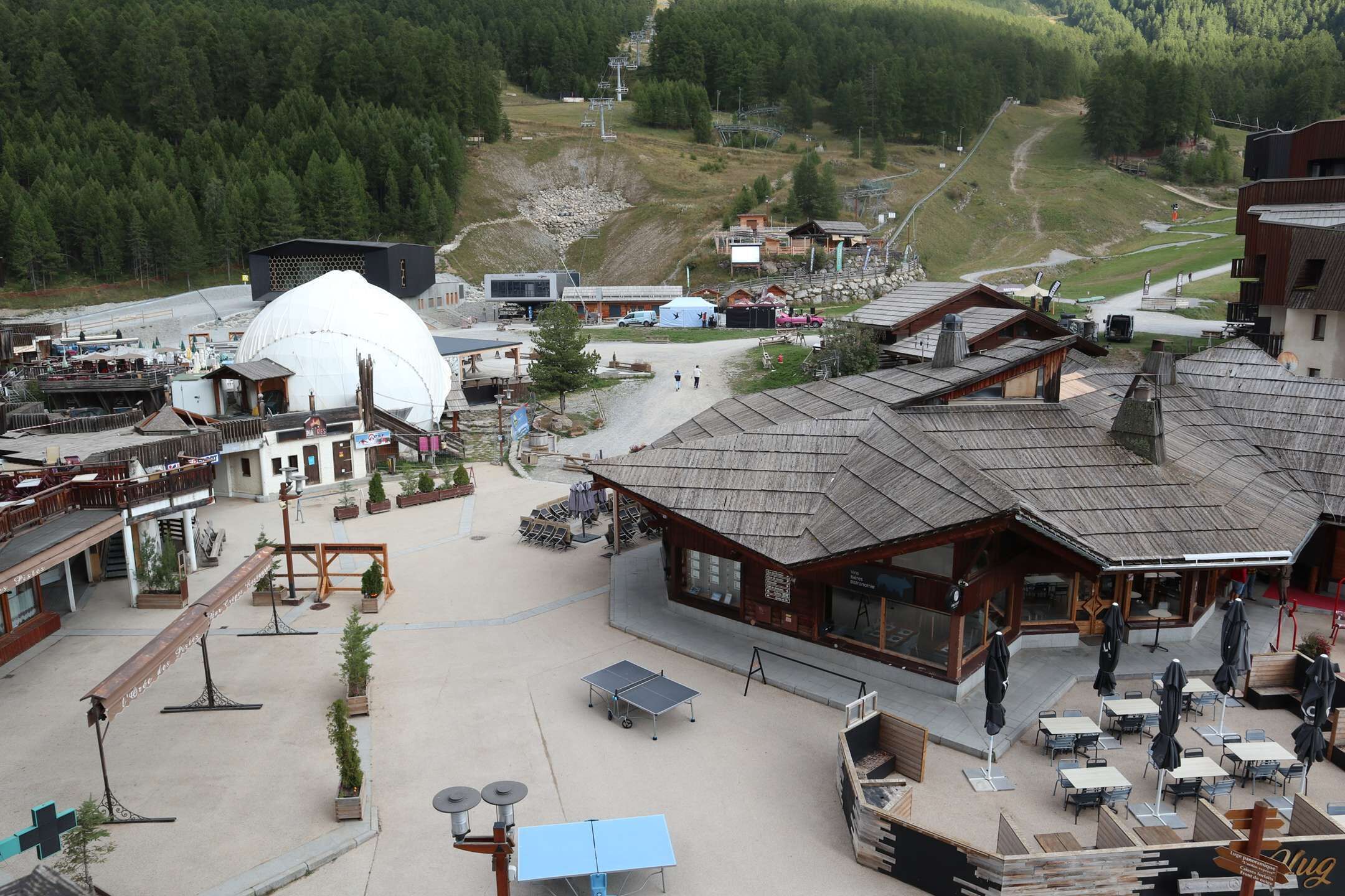 Un centro de esquí con una gran cúpula de nieve, asientos al aire libre y vistas a la montaña.