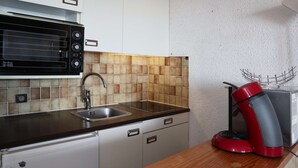 A kitchen with a built-in microwave, a sink, and a red coffee maker on the countertop. - COEUR STATION LES ORRES - Res. CAIRN - Studio 4 pers (LES ORRES 1650)