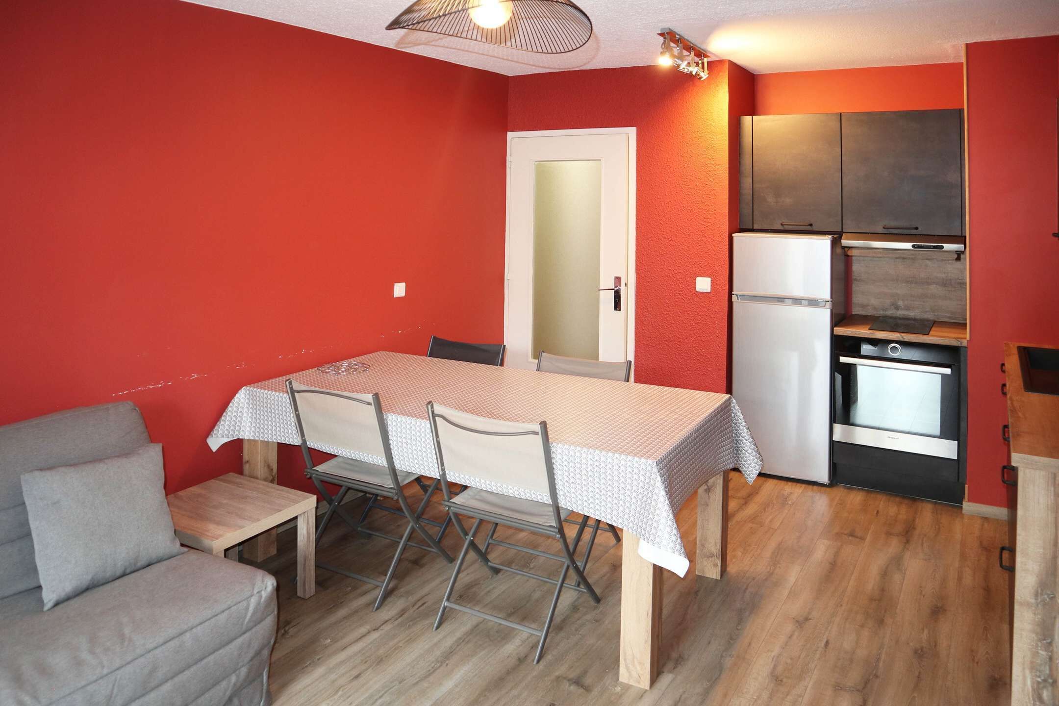 A compact kitchen with a refrigerator, oven, and wooden cabinets.