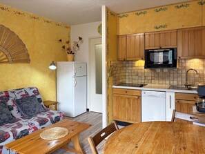 A compact living space with a kitchenette, a dining area, and a sofa with patterned cushions. - STUDIO 4 PERSONS RESORT CENTER (LES ORRES 1650)