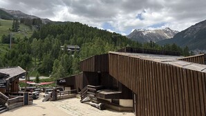 Een houten gebouw met een balkon, een restaurant en een bergachtige achtergrond.