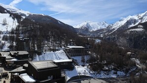 Un pueblo montañoso con picos nevados, edificios de madera y un telesilla.
