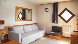 Una habitación compacta con sofá, una mesita, un armario y un radiador.