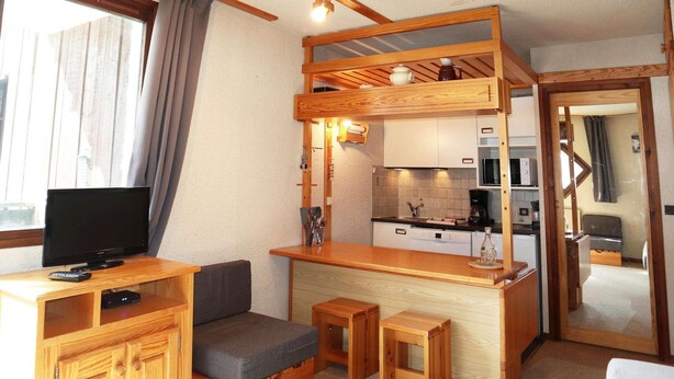 Un espacio habitable pequeño con kitchenette, televisor y zona de estar.