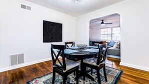 A dining area with a round table, four chairs, and a patterned rug.