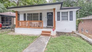 A single-story house with a front porch, a black door, and a brick exterior.
