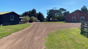 A rural property with a dirt driveway leading to a red barn and a black shed. - Farm House Accommodation Northern end of the Bay of Fires 5 mins from Mt Willian (Musselroe Bay)