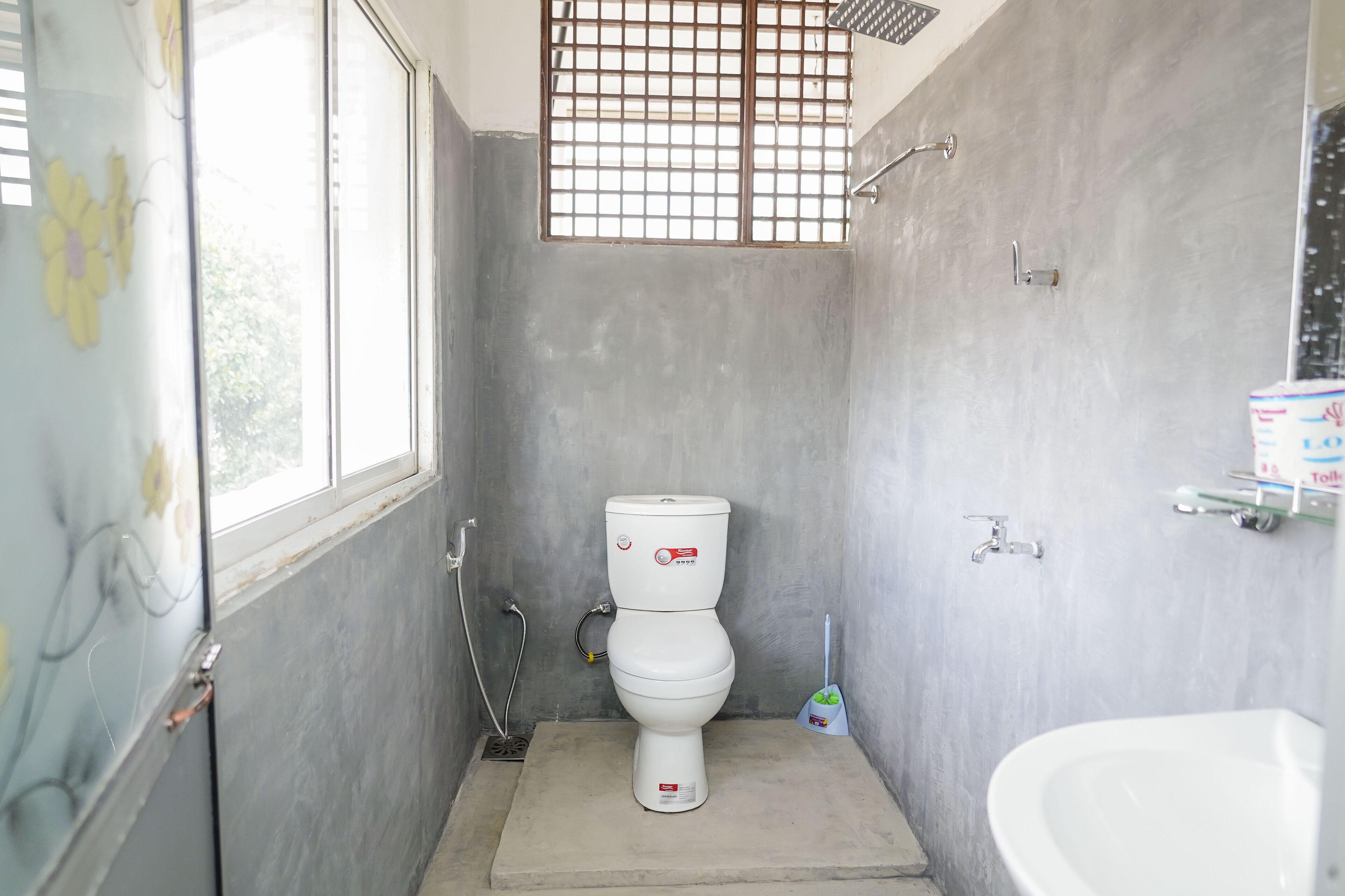 Een kleine, praktische badkamer met toilet, wastafel en raam.