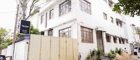 Un edificio blanco con múltiples ventanas, una puerta de madera y un letrero que dice 'The Anam'.