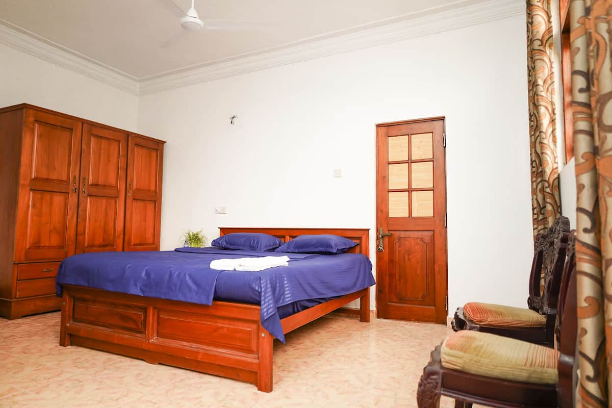 Un dormitorio con una cama de madera, un armario, una puerta y una silla.