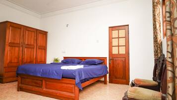 A bedroom with a wooden bed, a wardrobe, a door, and a chair.