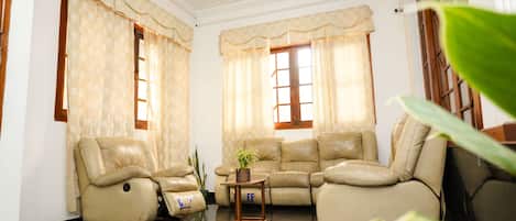 A living room with beige leather sofas, a small wooden coffee table, and a potted plant.