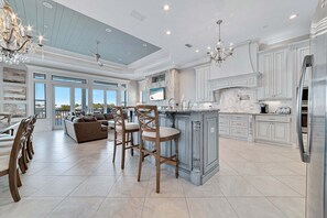 A spacious kitchen with a large island, bar stools, and a dining area with a sofa and chairs.