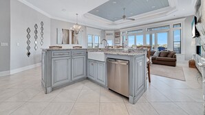 A spacious kitchen with a large island, modern appliances, and a dining area with a brown sofa. - Large Private Home Sleeping 16 On Cotton Bayou (Orange Beach)