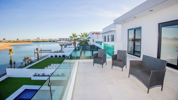 Une terrasse extérieure moderne dotée d’une piscine, d’un espace salon et offrant une vue sur la plage et la mer.