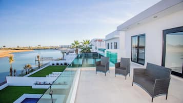 Une terrasse extérieure moderne dotée d’une piscine, d’un espace salon et offrant une vue sur la plage et la mer.