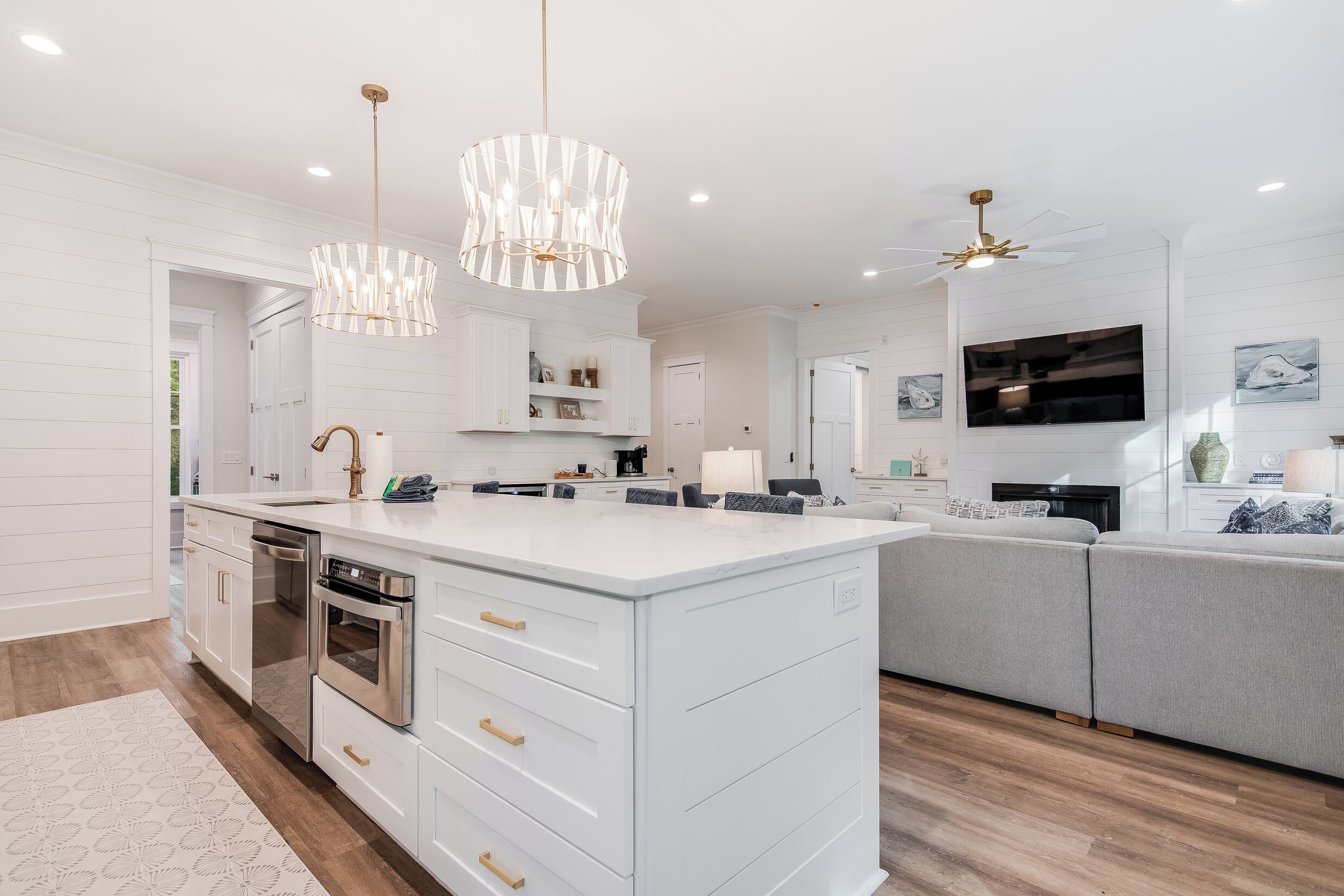 A modern kitchen with white cabinetry, a large island, stainless steel appliances, and pendant lighting.