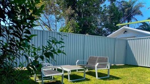 A fenced backyard with a small shed, a metal table and two chairs. - Homely Vibes 3BR Garden (Padstow)