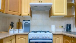 A kitchen with wooden cabinets, a gas stove, an oven, and a microwave. - Homely Vibes 3BR Garden (Padstow)