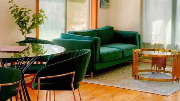 A modern living room with a green sofa, a round coffee table, and matching chairs. - Homely Vibes 3BR Garden (Padstow)