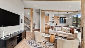A modern living room with a sofa, coffee table, and TV stand. There is a staircase leading to another level.