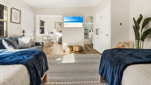 Un dormitorio moderno con dos camas, un televisor grande y vista al mar.