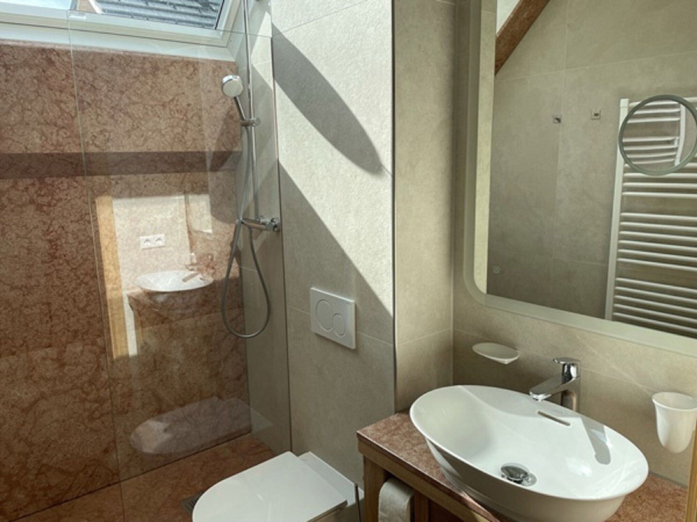 A modern bathroom with a glass-enclosed shower, a white sink, and a mirror above the sink.