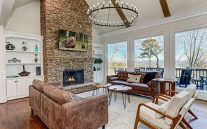 A spacious living room with a stone fireplace, leather sofas, and a view of the outdoors. - McElroy Manor - Luxury and comfort in Big Canoe! (Jasper)