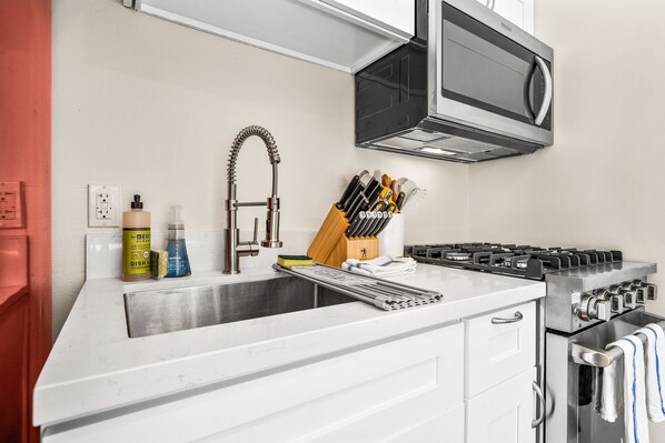 A kitchen with a stainless steel sink, a range hood, and a gas stove.