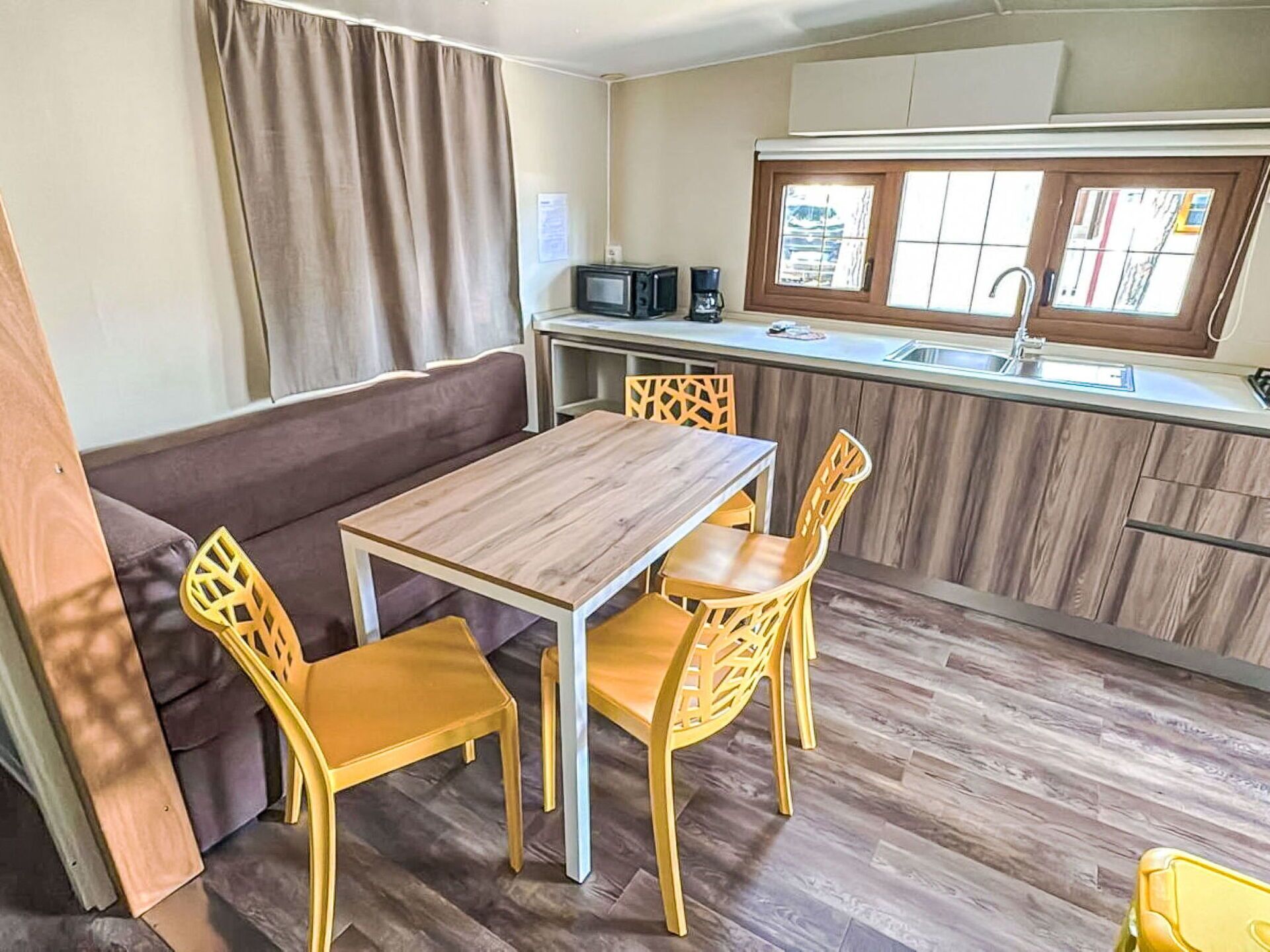 Cocina compacta con mesa y sillas de madera, microondas y ventana con vistas.