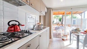 A modern kitchen with a gas stove, kettle, and sink. There is a window with blinds and a view of the outdoor patio area. - Nice apartment in villa for 6 guests with WIFI, pool, A/C, TV and terrace (Ca' Savio)