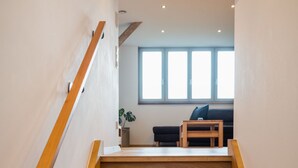 Una escalera de madera que conduce a una sala de estar con un sofá y una mesa de centro.