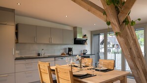 Una cocina moderna con armarios grises, una mesa de comedor de madera con sillas y un ventanal con vistas al exterior.