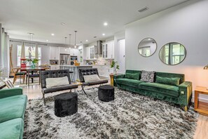 Un salon moderne avec un canapé vert, un pouf noir et un tapis moelleux.