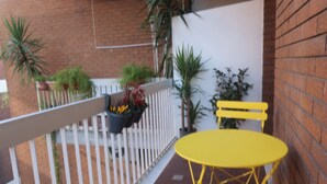 A balcony with yellow outdoor furniture, potted plants, and a white railing. - The Yellow Petal (Verona)