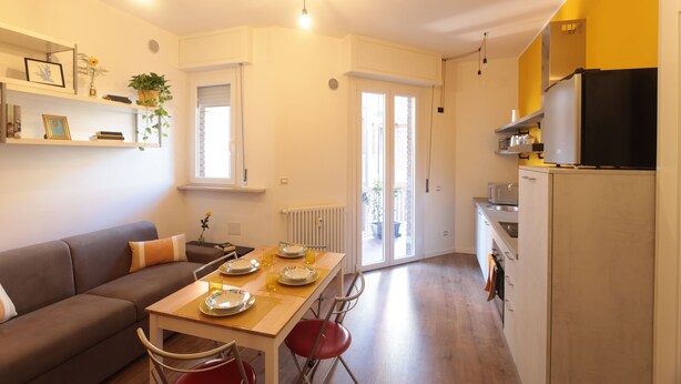 A modern apartment with a dining area, kitchen, and living room. - The Yellow Petal (Verona)