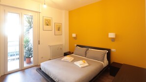 A bedroom with a bed, bedside tables, a radiator, and a potted plant. - The Yellow Petal (Verona)
