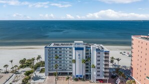 Ett hotell vid stranden med en pool, en parkeringsplats och utsikt över havet.