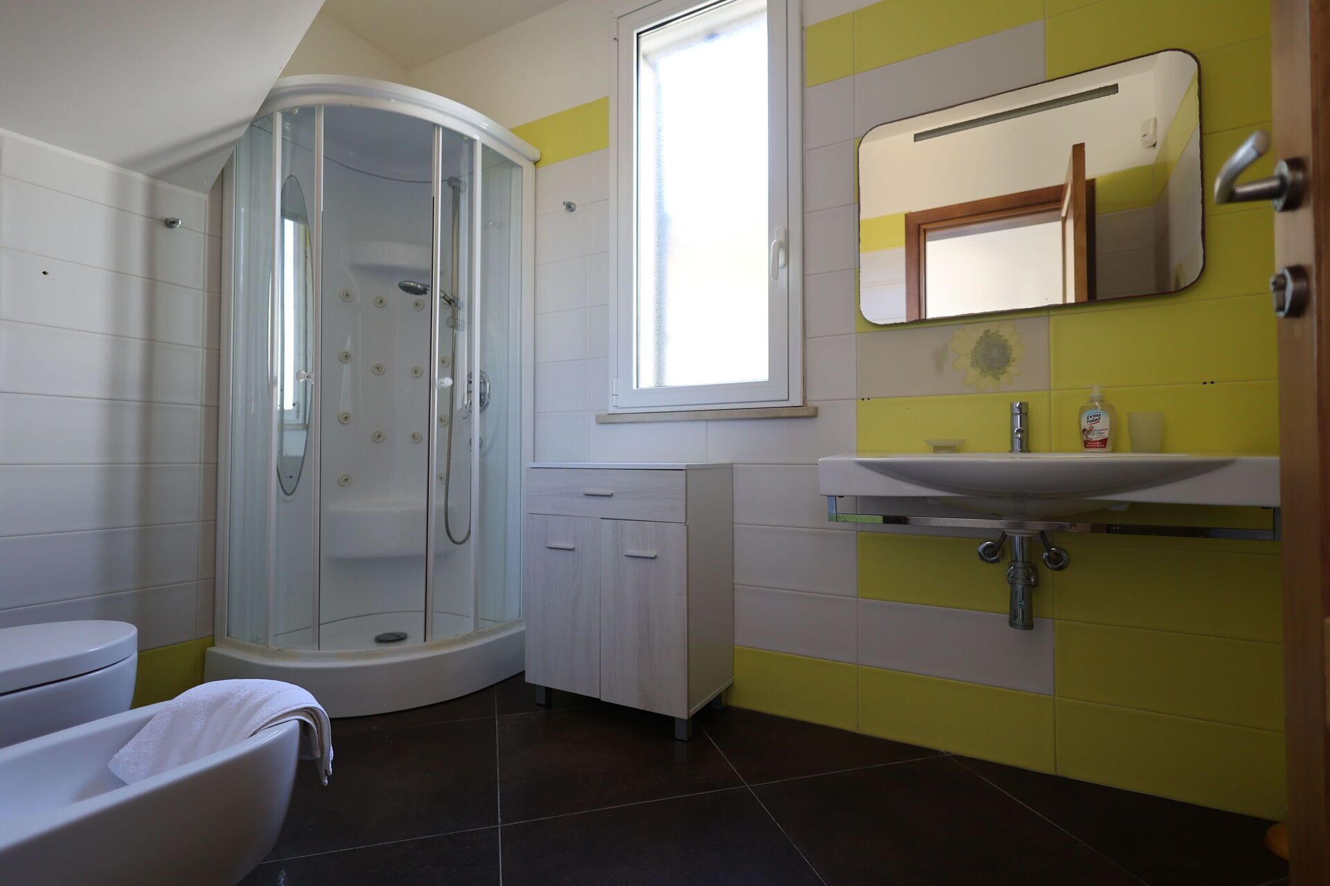 Un baño moderno con cabina de ducha de vidrio, inodoro y lavamanos con espejo.