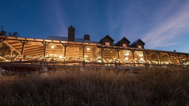 A row of log cabins with a covered walkway, string lights, and a clear sky. - Selah Springs Ranch- Large Family Reunion/Retreat Ranch on the River- Sleeps 60 (Brady)