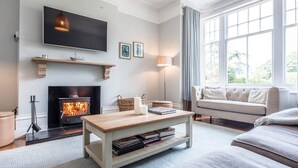Un salon confortable avec une cheminée, un téléviseur à écran plat, un canapé et une table basse.
