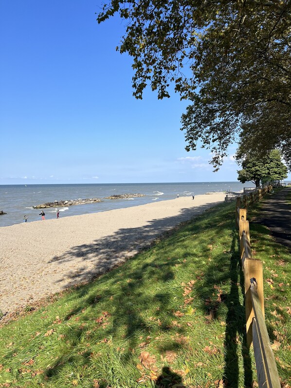 En strand med et træhegn, græsareal og klar himmel.