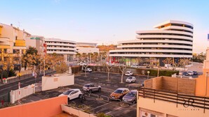 Een modern hotel met een gebogen gevel, meerdere verdiepingen en een parkeerplaats met verschillende auto's.