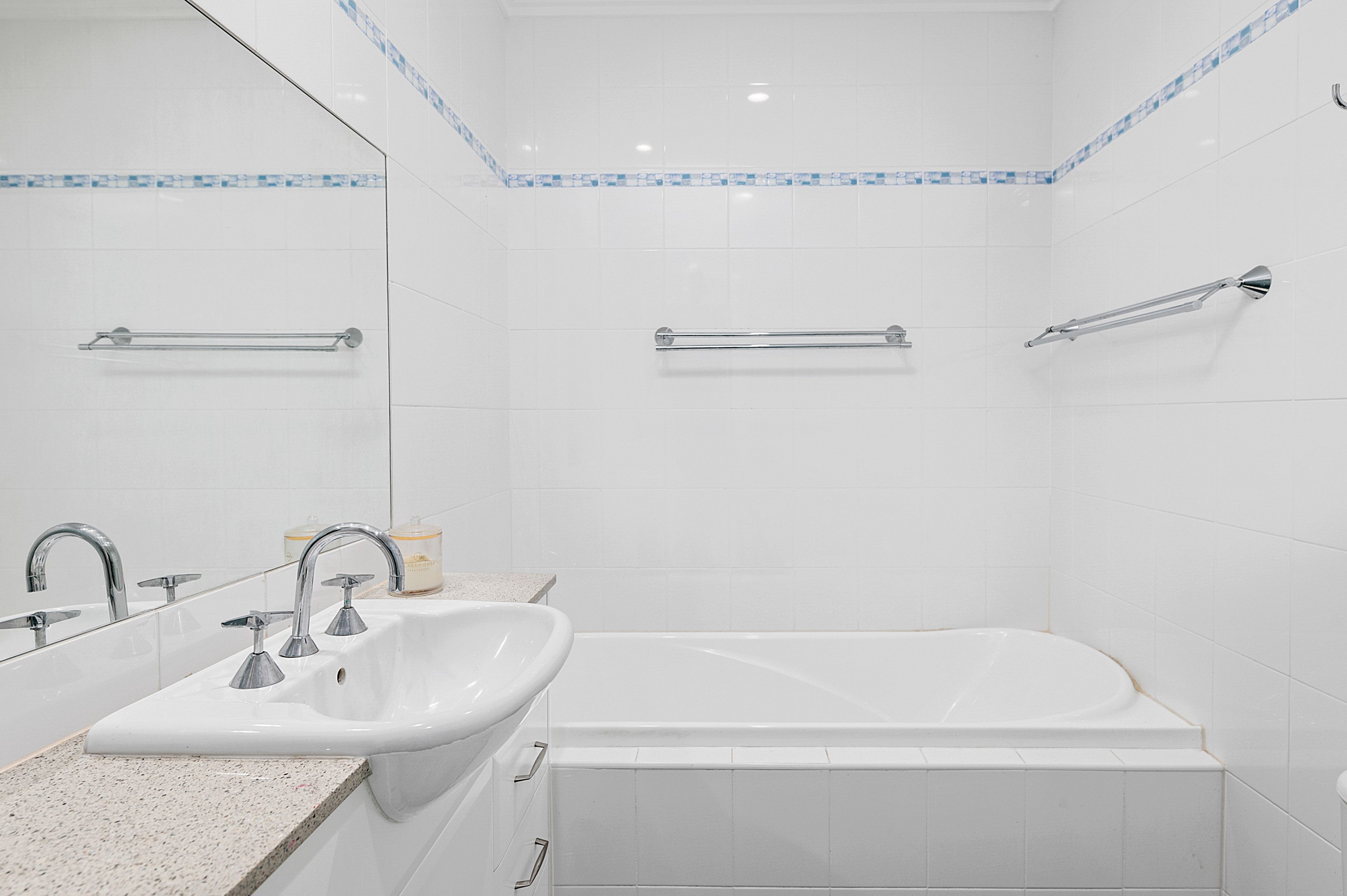 A bathroom with a bathtub, a sink, and a mirror.