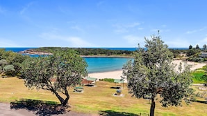 Paisatge costaner amb una platja, zones de pícnic i arbres.
