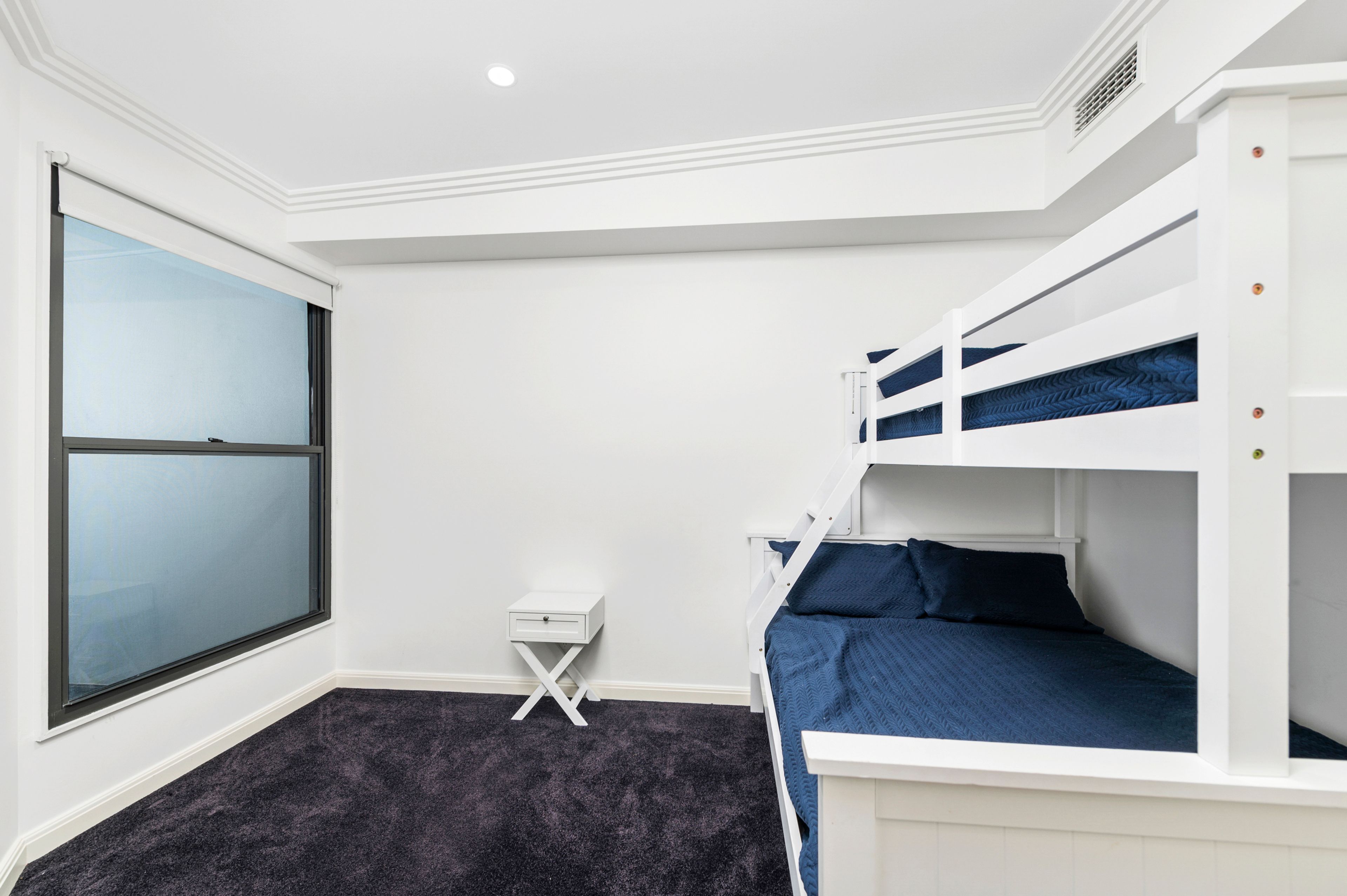 Una habitació amb lliteres, una taula de nit petita i una finestra.