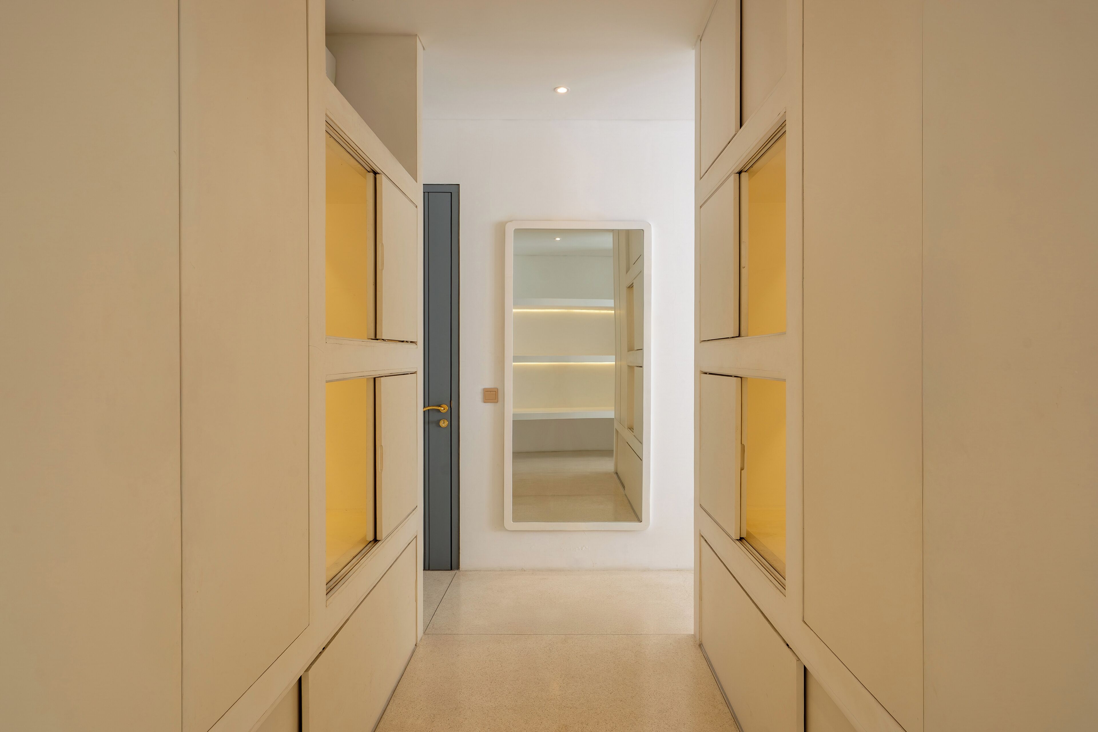 A narrow hallway with a central door leading to a room with a mirrored closet.